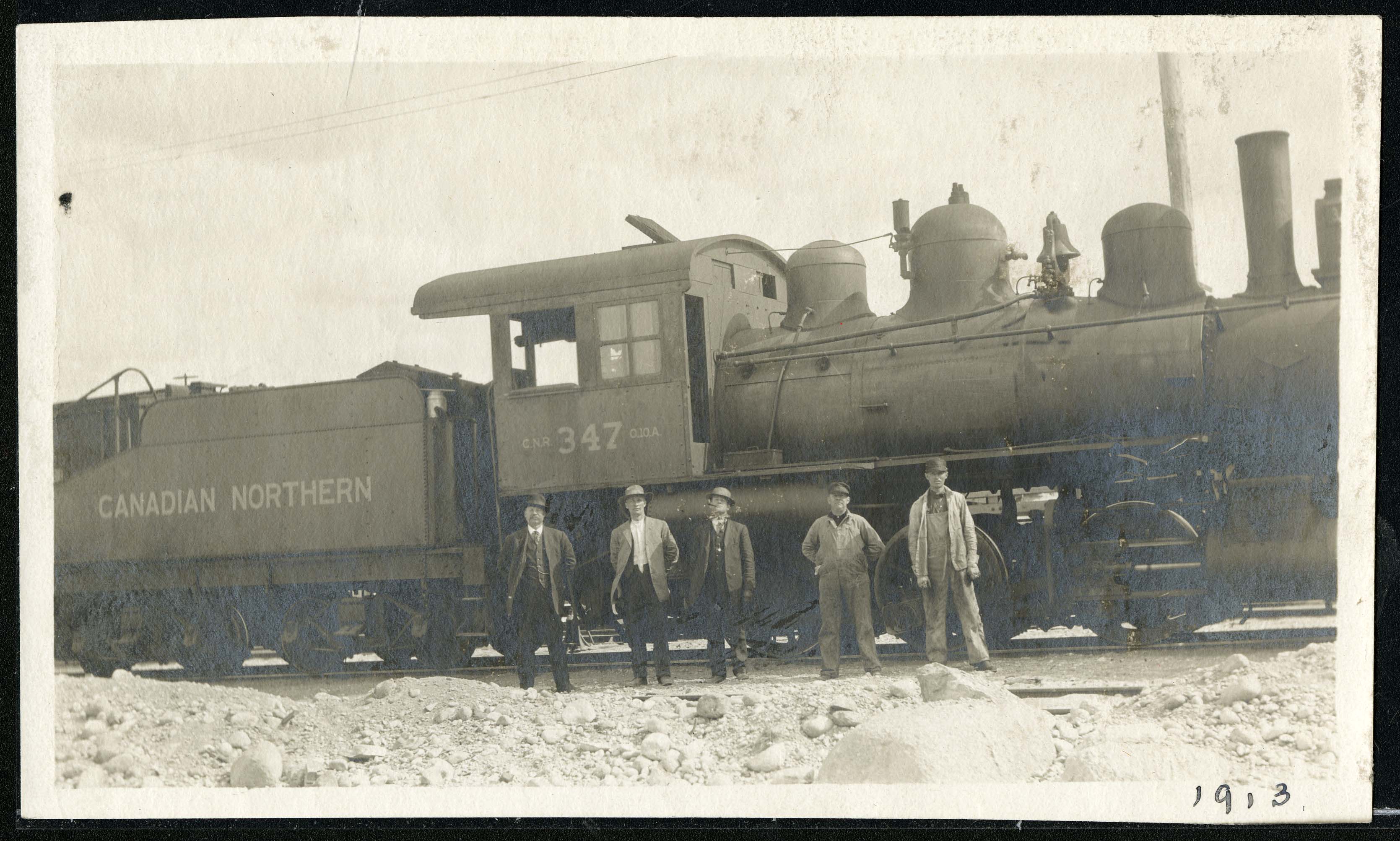 Men in front of train engine in an archival photo.