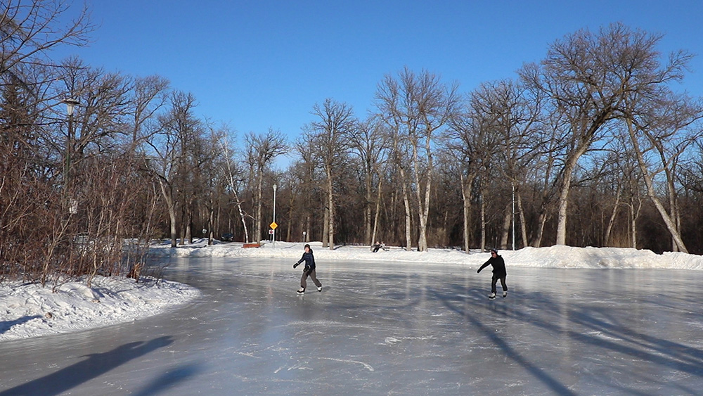 Two people ice skating on a frozen pond.