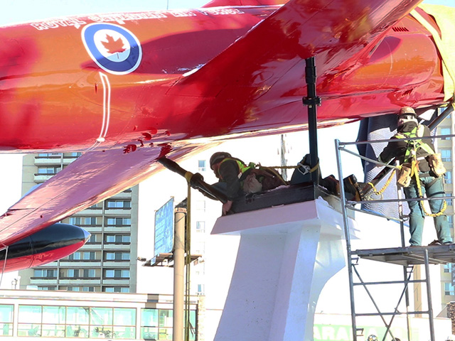 Two workers repairing the structural supports on an airplane installation