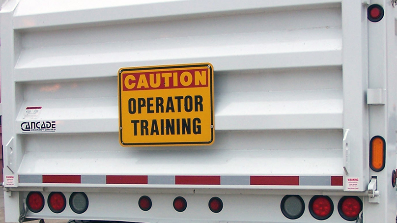 "Caution Operator Training" sign on white truck