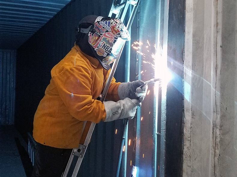 A student wearing protective gear welds.