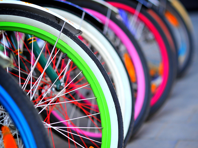 A close up of a row of colourful bike tires and spokes