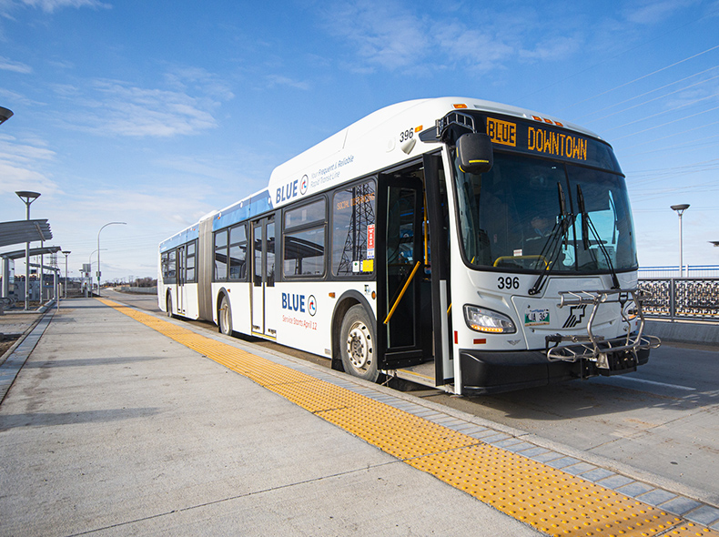 A rapid transit route bus sits beside the curb