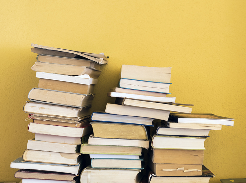 Books Stacked in front of yellow wall