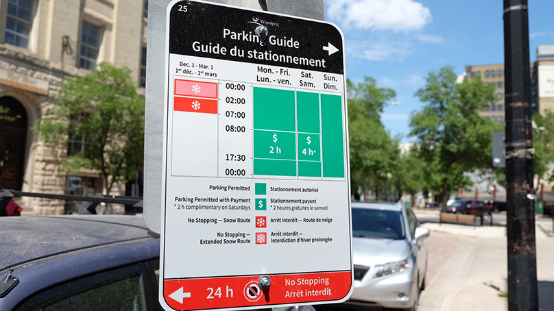 A street sign labelled "Parking Guide" with an arrow pointing to the right at the top and a timetable for when parking is free, paid, or prohibited sorted by day of the week and time