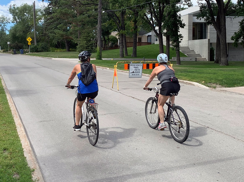 Two people biking on an open street