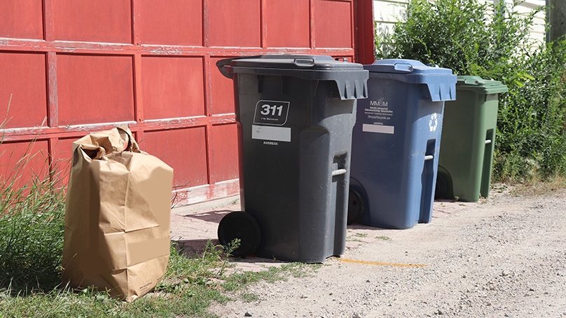 Curb showing garbage recycling and food waste bins