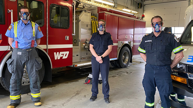 Winnipeg fire paramedic service members wearing respirator masks in front of fire truck
