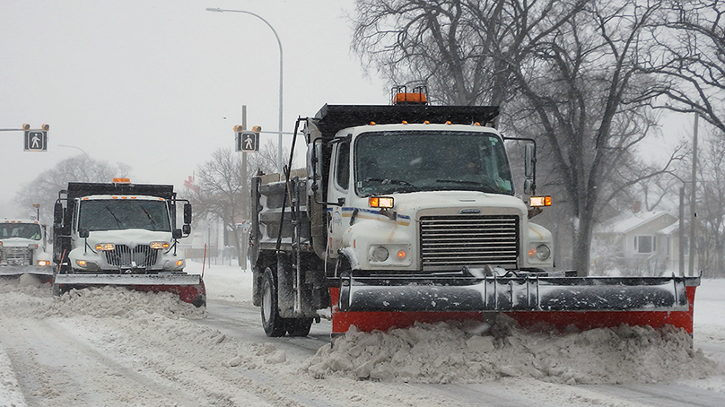three snow plows in a row plowing a road