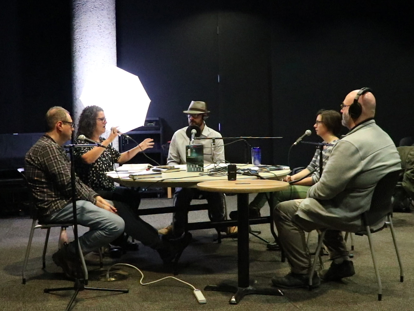 Five people sitting at a table recording the Time to Read podcast in the Carol Shields Auditorium at the Millennium Library