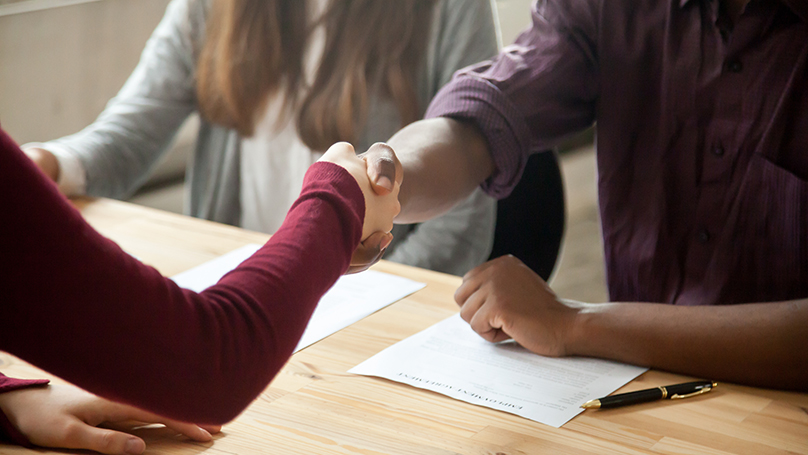 People interviewing at table shaking hands