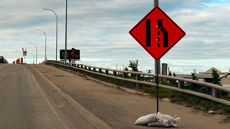 Lane closed road work sign on a bridge ahead of construction zone.