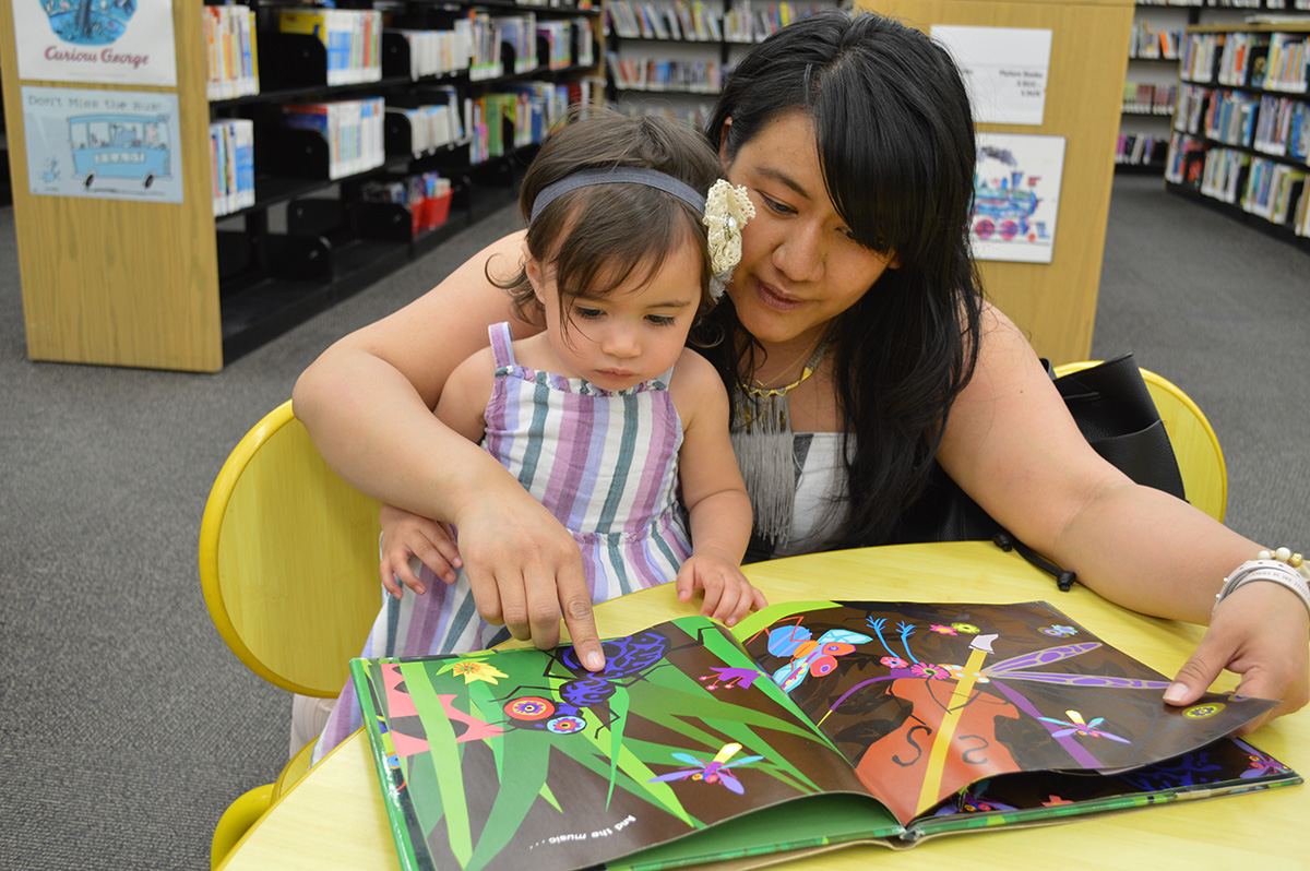 A woman reads a children's book to a little girl.