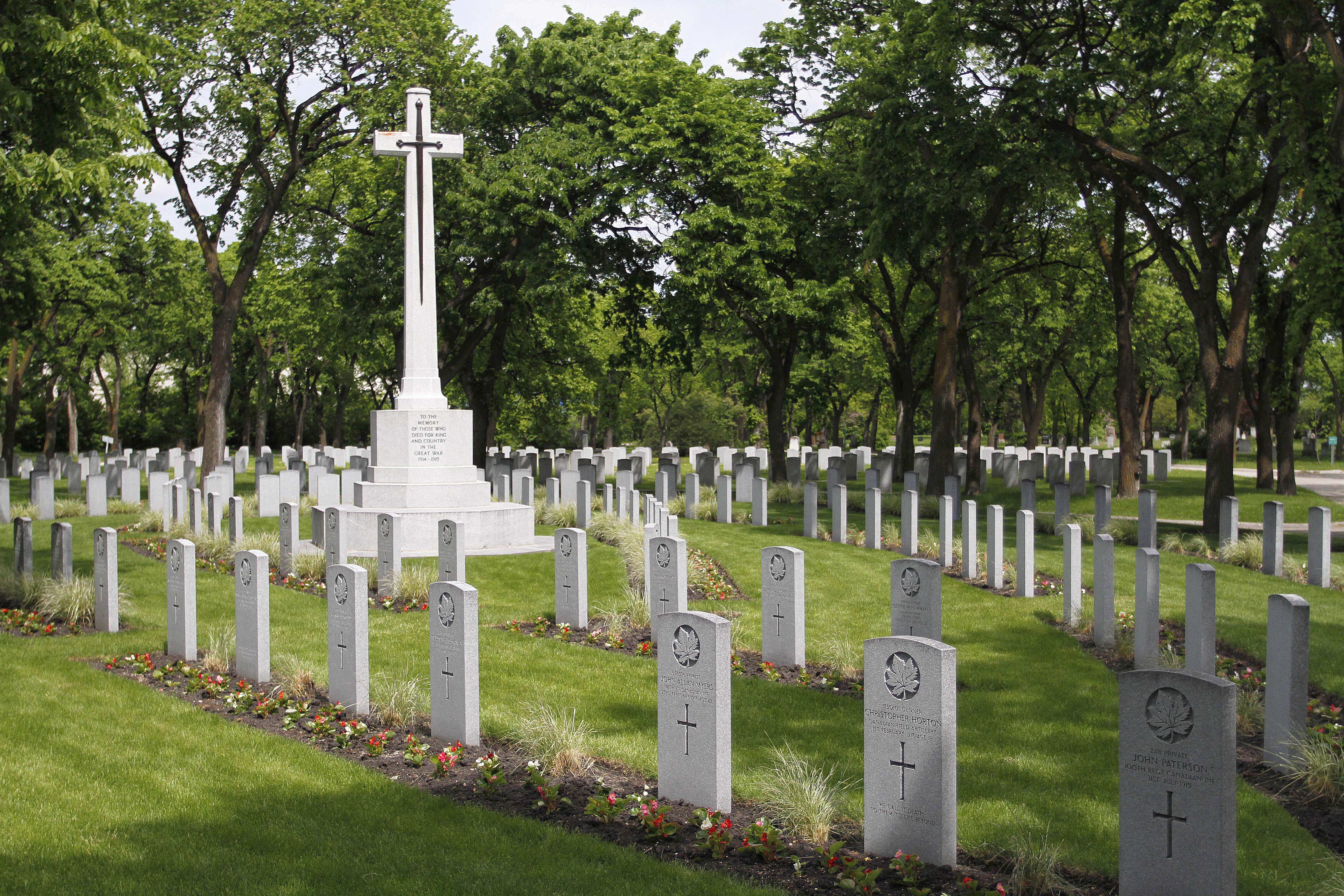 Gravestones are seen with a large white cross in the middle.