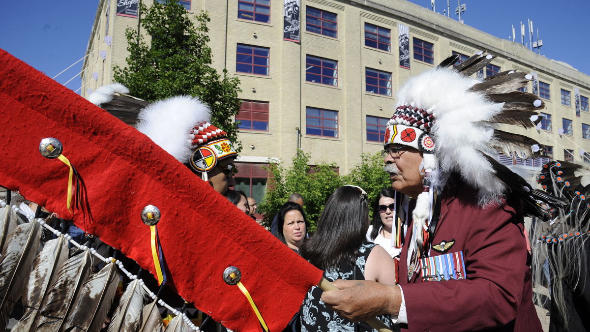 A veteran in a headdress leads the grand entry at a ceremony.