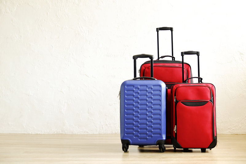 One blue suitcase and two red suitcases stand in a room.