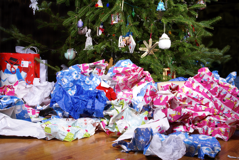 Used wrapping paper sits on the ground beside a Christmas tree.