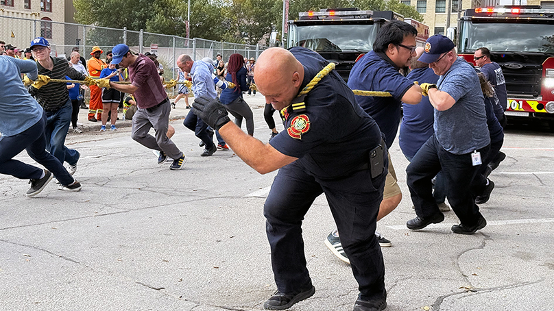 Group of people pull a fire engine with a rope.