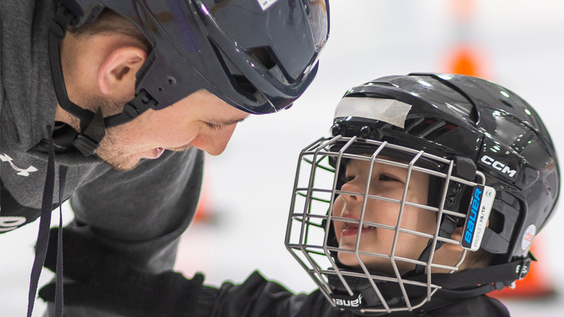 Smiling dad crouches down to speak to son at skating