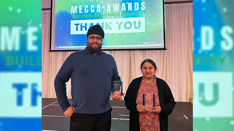 Two people standing holding awards