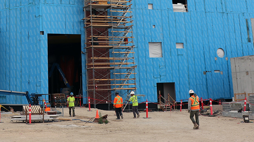 Construction workers outside of a building under construction.