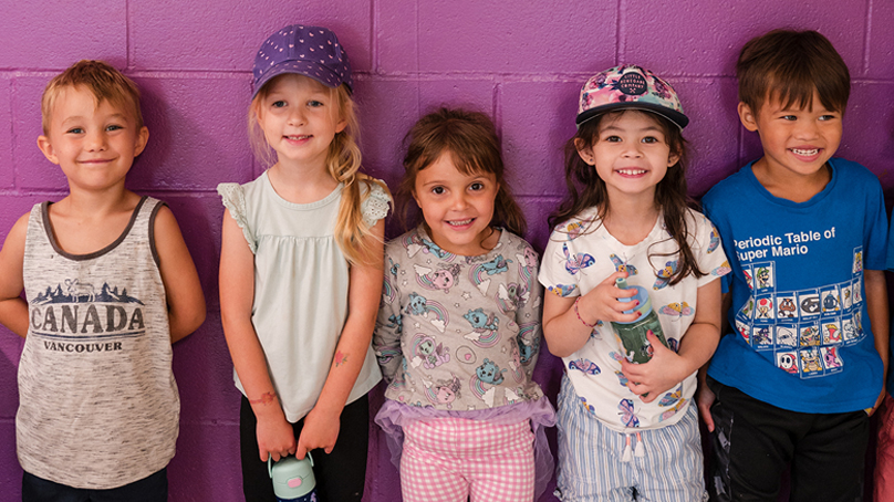 5 preschoolers standing in front of purple wall