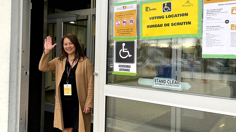 election worker waving at the door of a voting location