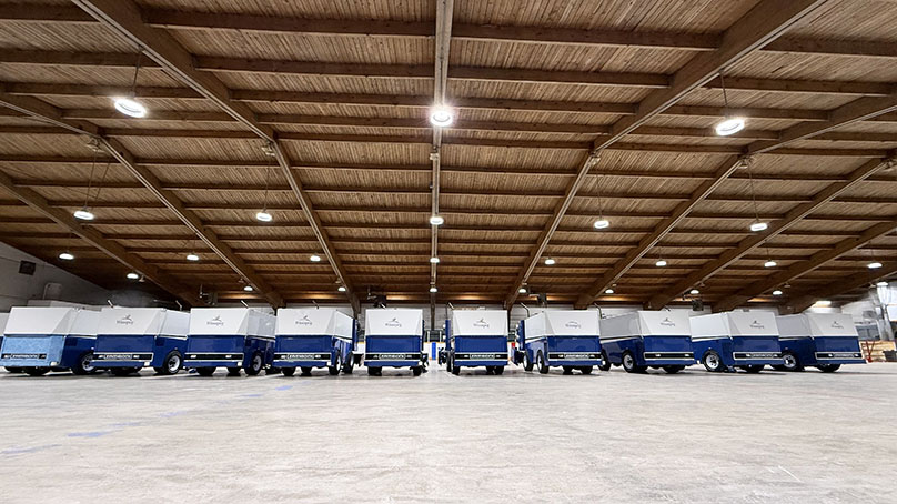 a line of Zambonis in side an empty arena with no ice