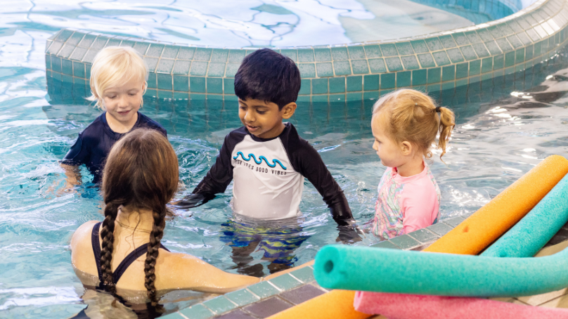 Three children in a pool with a swim instructor