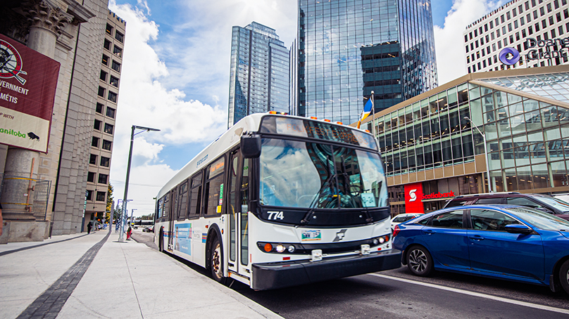 Winnipeg Transit bus stopped in downtown Winnipeg. Display reads Folk Fest Express.