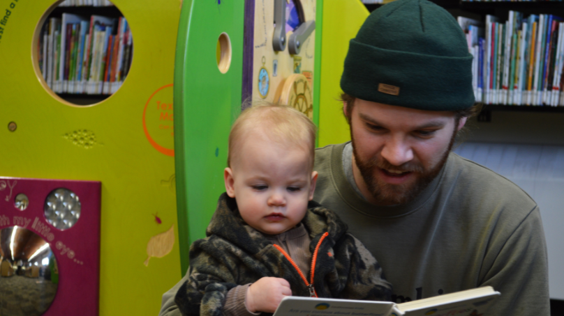 Man reading a book with a child