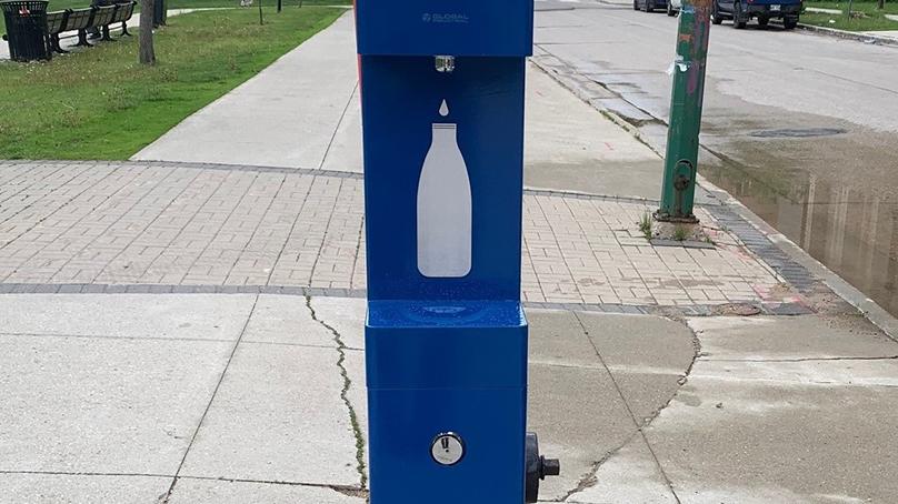 Front of blue hydration station with image of white bottle on the sidewalk.