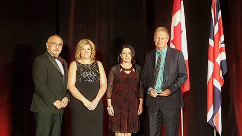 Four people standing on a stage and being presented an award.