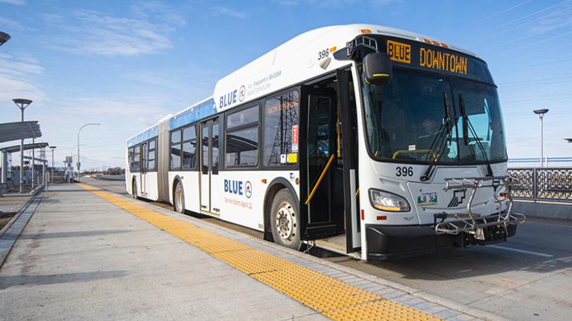 A rapid transit route bus sits beside the curb