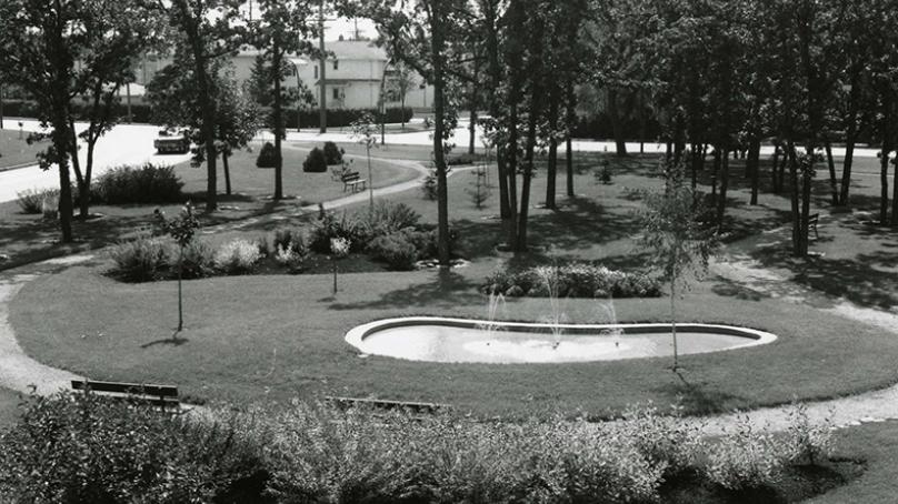 A circular mini-park with a fountain is displayed in black and white