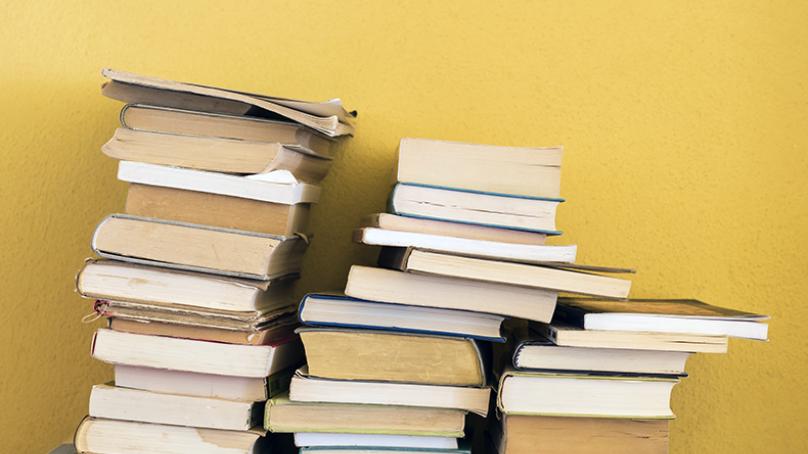 Books Stacked in front of yellow wall