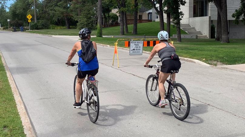 Two people biking on an open street