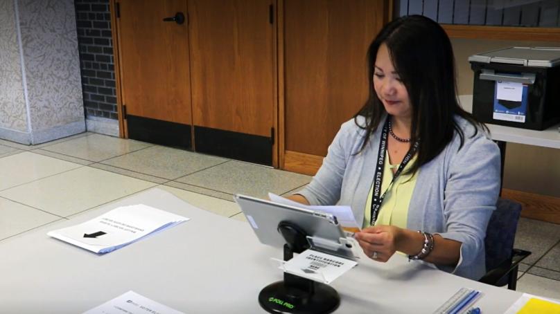 An election worker scanning a piece of paper with a tablet.