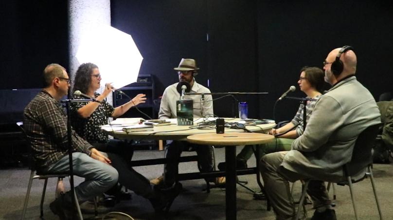 Five people sitting at a table recording the Time to Read podcast in the Carol Shields Auditorium at the Millennium Library