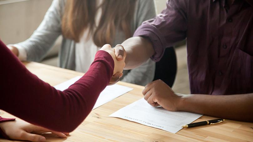 People interviewing at table shaking hands