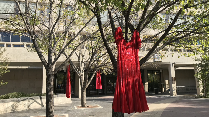 Red dresses hang from trees in the City Hall courtyard to raise awareness on violence against Indigenous women, girls and two-spirited peoples
