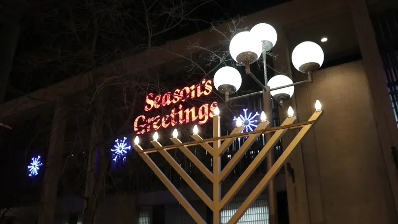 City hall Council building with seasons greetings and snowflake lights with the lit menorah in front