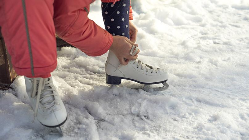 Person lacing up their skates on an outdoor rink