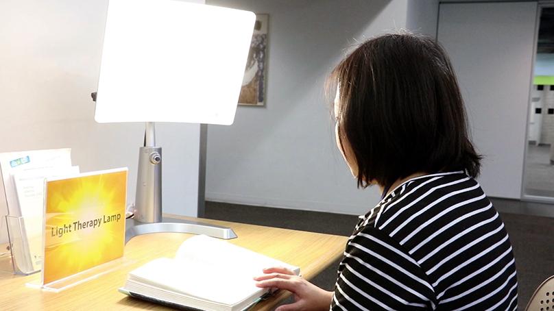 person sitting in front of an on light therapy lamp