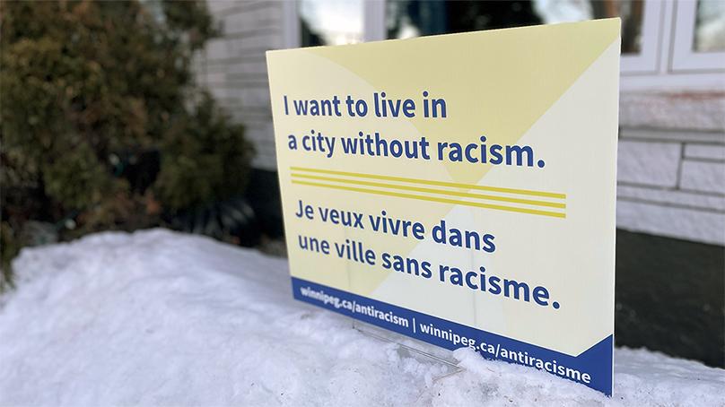 Lawn sign displaying 'I want to live in a city without racism' in a snow bank