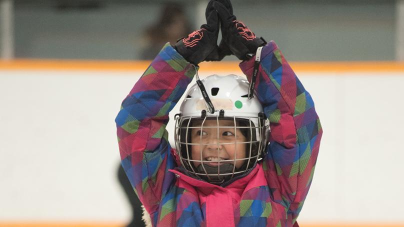 Closeup of girl skating with arms up and hands clasped above her head