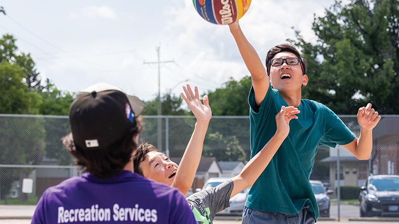 Recreation Program leader and two youth playing basketball at Summer camp