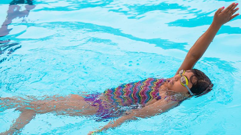girl swimming on her back in a pool