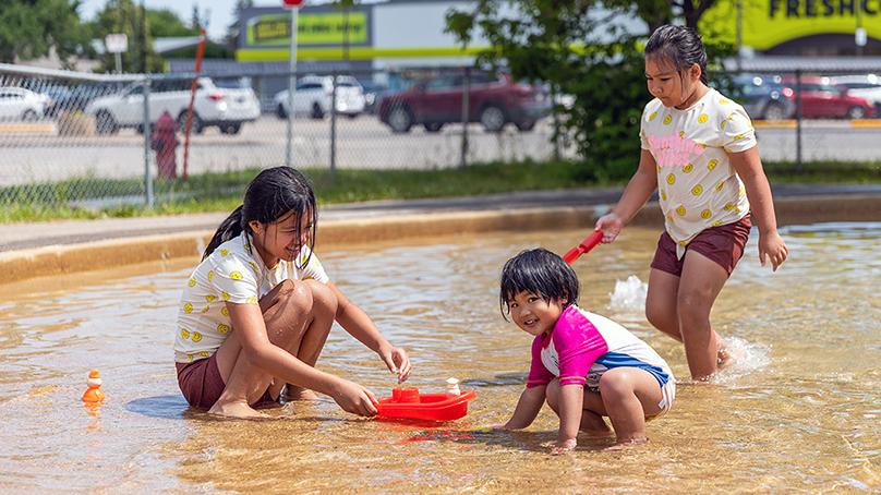 Girls playing in a wading pool with water toys