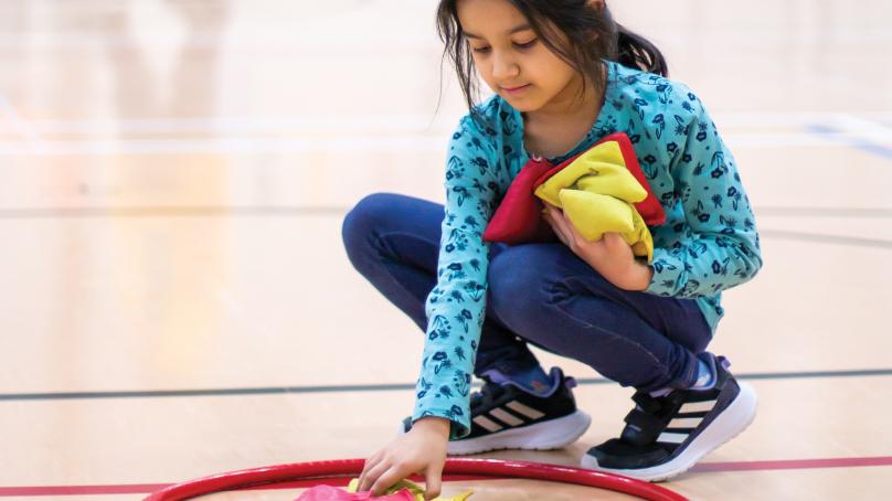 Girl playing game with beanbags and hula hoop